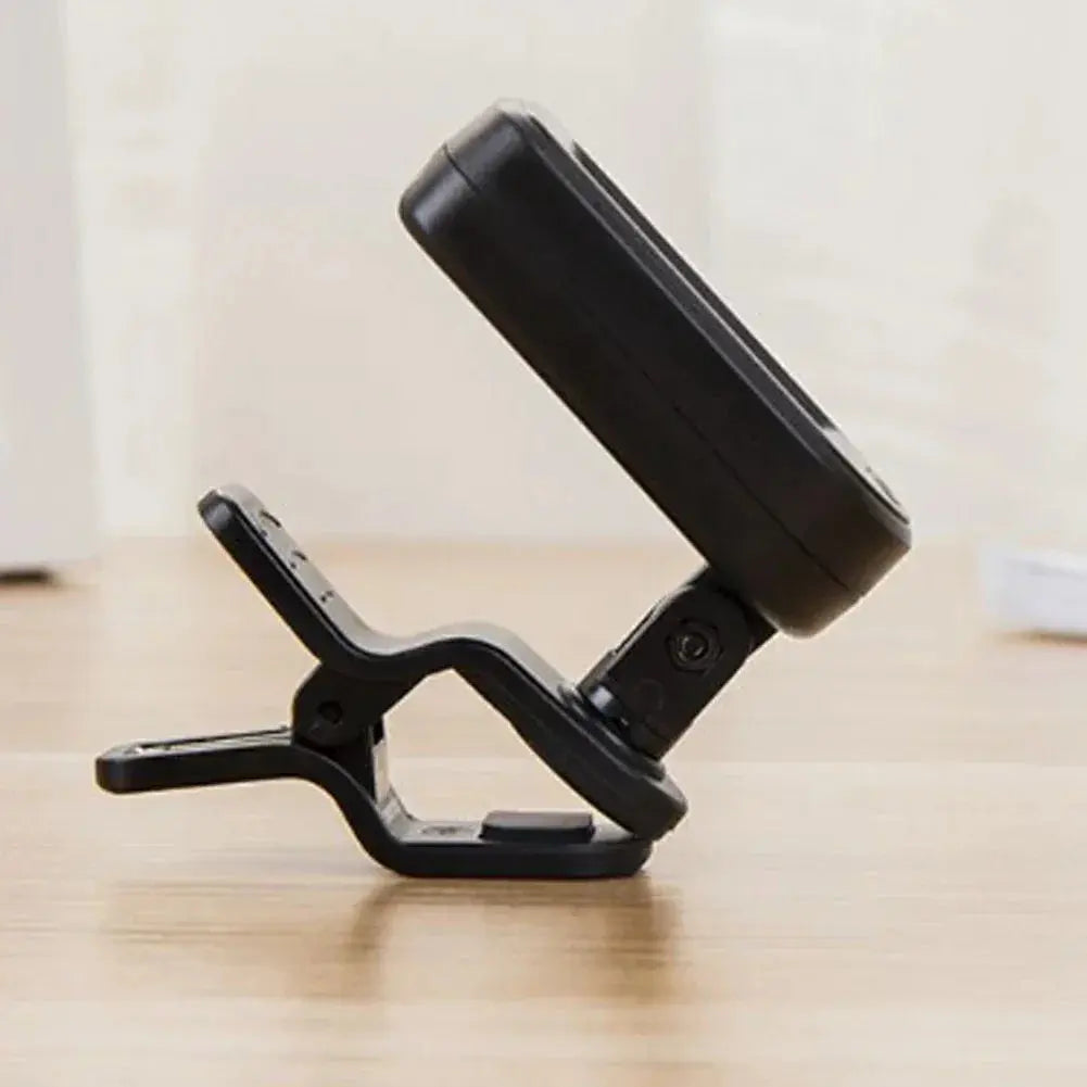 Digital guitar tuner with clip, black, placed on wooden surface