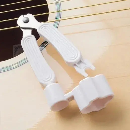 White 3-in-1 guitar string winder, string cutter, and bridge pin puller on acoustic guitar