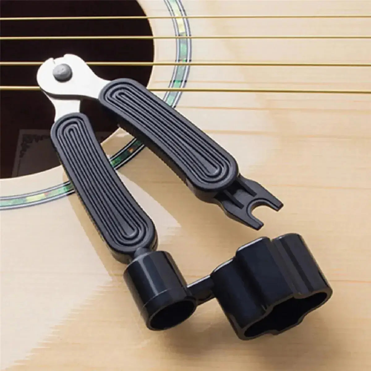 3-in-1 guitar string winder, cutter, and bridge pin puller tool on acoustic guitar body