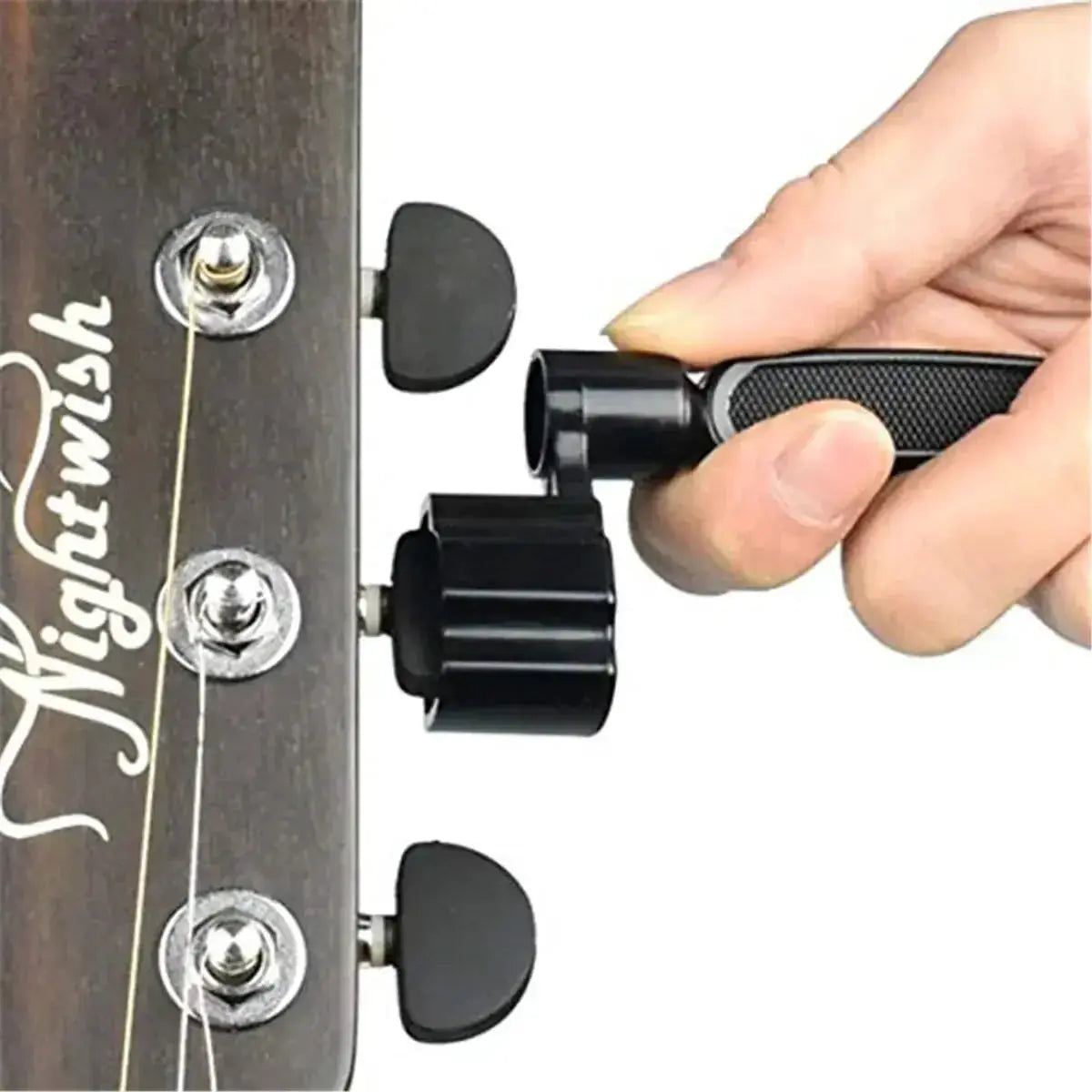 Hand using a guitar string winder tool to tune acoustic guitar headstock