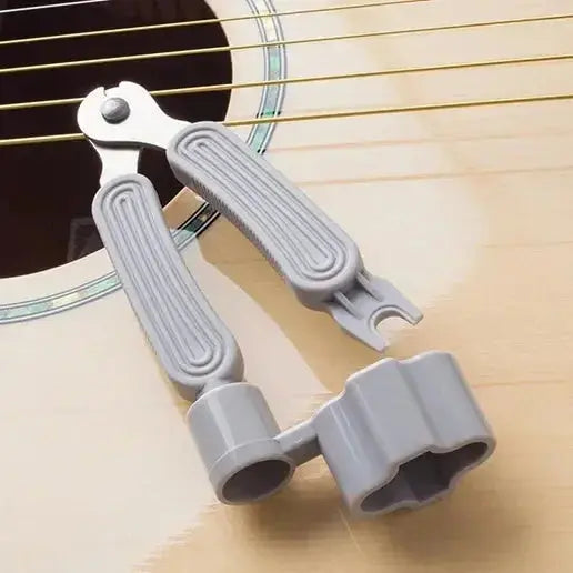 3-in-1 guitar string winder, string cutter, and bridge pin puller tool on acoustic guitar